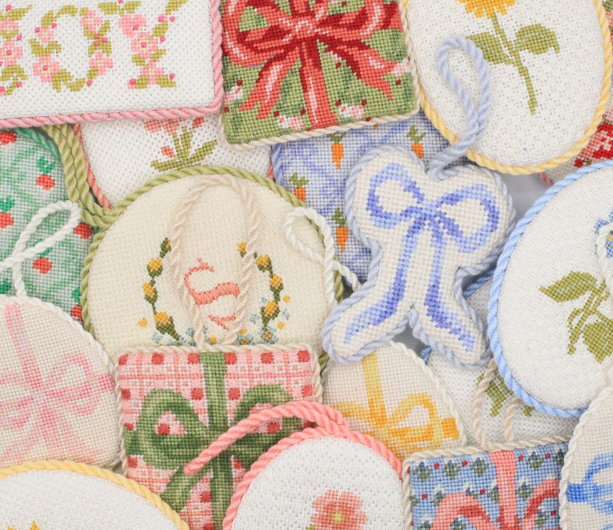 Many finished needlepoint projects with different designs are clustered together.