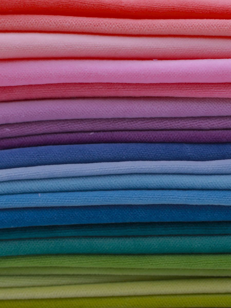Several colored velvet fabrics are stacked on top of each other. Velvet fabric for self finishing needlepoint. 