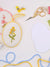 Flower needlepoint ornaments sit atop a table with supplies and tools for self finishing your needlepoint. 