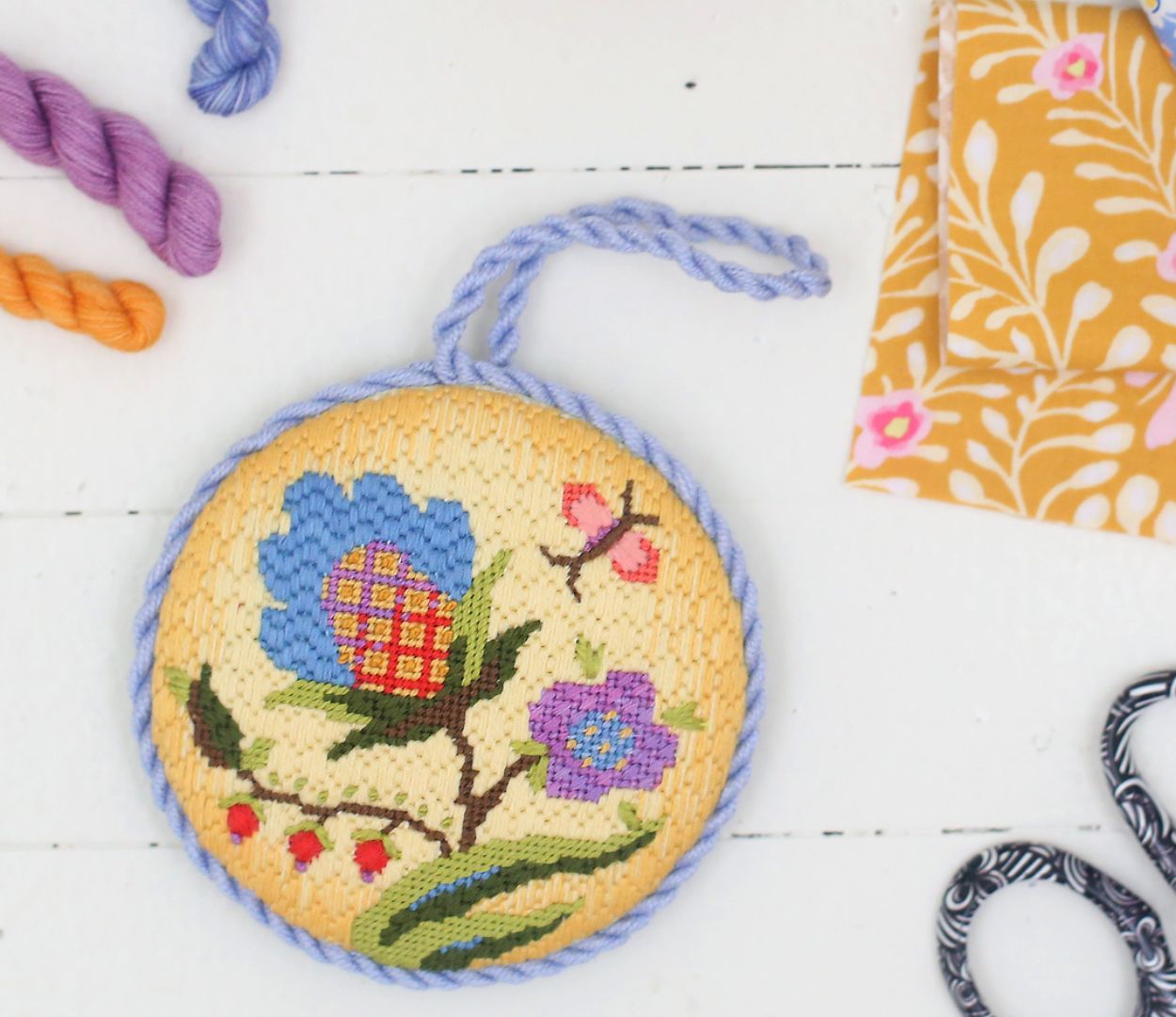 Finished ornament with cording sits atop a table with supplies.