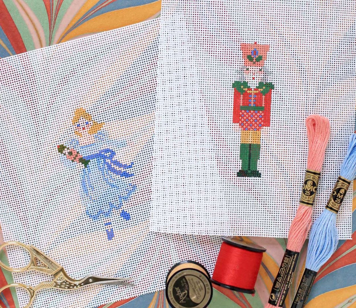 Two painted Nutcracker themed charts sit atop a table next to supplies.