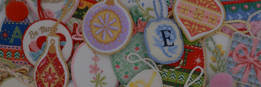 Several needlepoint ornaments lay in a cluster.